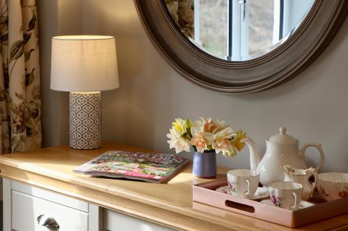 a table with a lamp and cups and a mirror at The New Inn Halse in Taunton