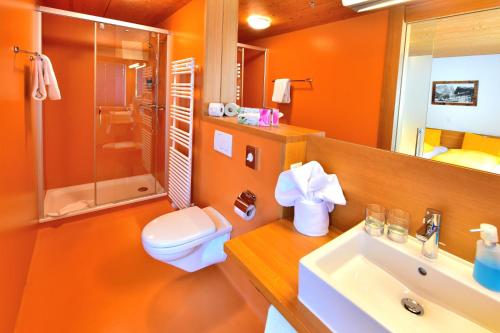 an orange bathroom with a toilet and a sink at Hotel Wetterhorn in Grindelwald