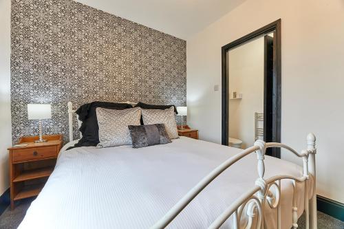 1 dormitorio con 1 cama blanca grande y espejo en Host & Stay - Blacksmith's Cottage en Amble