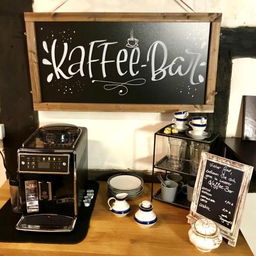 a table with a coffee maker and a black sign at Haus Buuck - Herberge in Rüthen