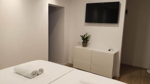 1 dormitorio blanco con 1 cama y TV en Fiorino Rooms Korčula, en Korčula