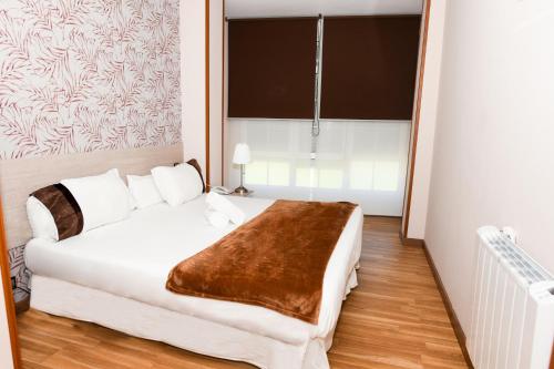 a bedroom with a white bed with a brown blanket at Hotel Ancora Urban Center in Finisterre