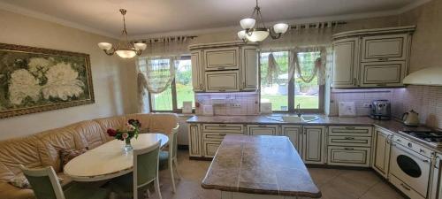 a kitchen with white cabinets and a table and a couch at Трушки34/1 in Trushki