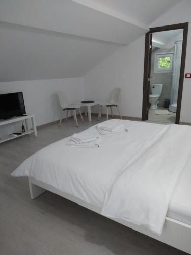 a white bedroom with a bed and two chairs at Casa Patryk in Orşova