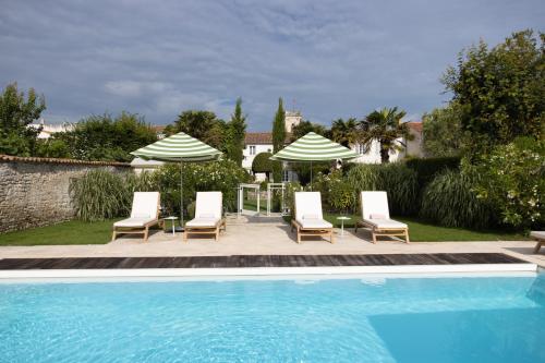 a pool with two umbrellas and chairs and a table and chairs at Villa Clarisse & Spa by Olivier Claire in Saint-Martin-de-Ré