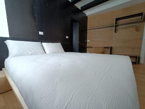 a bedroom with a white bed with a black headboard at Le Meridiane City Rooms In Trento in Trento