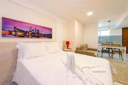 a white bedroom with a white bed and a desk at Pousada da Águia in Natal