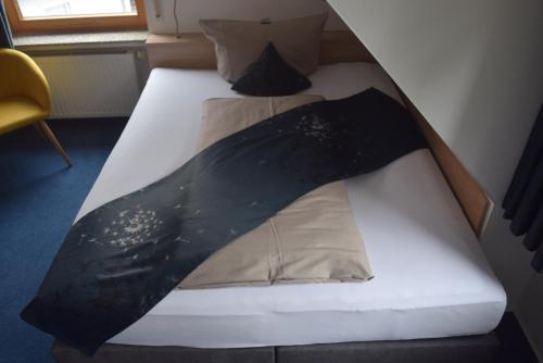 a bed with a black and white comforter on it at HOTEL BIKE & HIKE in Obersuhl