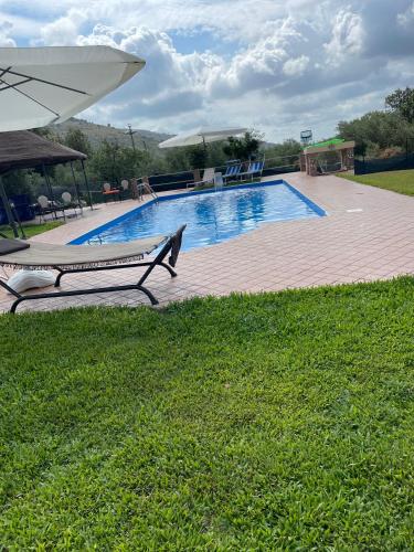 a swimming pool with two lounge chairs and an umbrella at Centro estivo Il Piccolo Paradiso in Sonnino