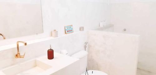 uma casa de banho branca com um lavatório e um espelho em Woman Trip Hostel Boutique - Arraial d´Ajuda em Arraial d'Ajuda