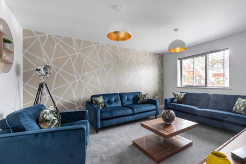 a living room with blue couches and a table at Elliot Oliver - The Old Surgery - Stunning 4 Bedroom Home With Parking In Cheltenham in Cheltenham