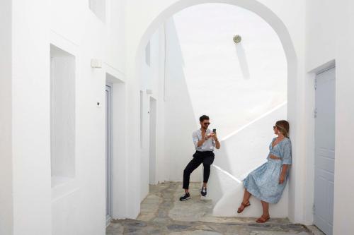 a man taking a picture of a woman standing next to a white wall at Mr and Mrs White Oia - Santorini in Oia