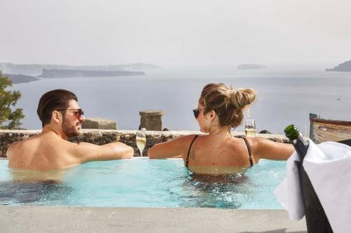 a man and woman sitting in a hot tub at Mr and Mrs White Oia - Santorini in Oia