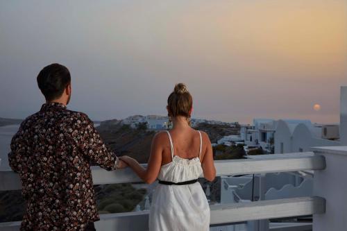 a man and woman standing on a balcony looking at the city at Mr and Mrs White Oia - Santorini in Oia