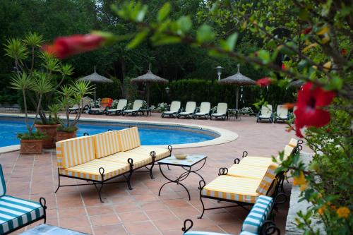 two benches and a pool with chairs and a table at Hotel Bahia in Paguera
