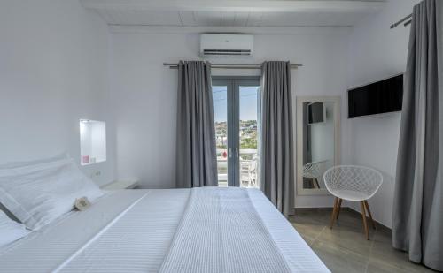 a bedroom with a large white bed and a balcony at Zeus Suite in Triovasálos