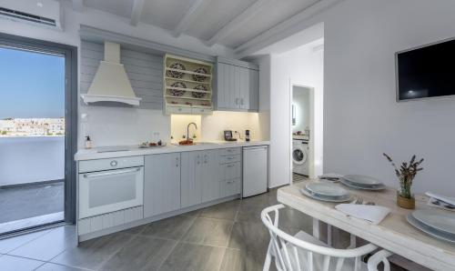 a kitchen with white cabinets and a dining table at Zeus Suite in Triovasálos