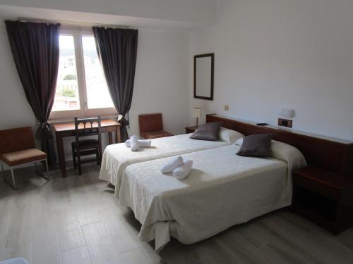 a bedroom with two beds and a desk and a window at Hotel Gesòria Porta Ferrada in Sant Feliu de Guíxols