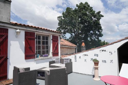 a patio with chairs and a table and a building at Maison de charme, d'artiste, décoration brocante in Aigrefeuille-dʼAunis