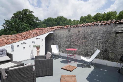 a patio with chairs and a table and a brick wall at Maison de charme, d'artiste, décoration brocante in Aigrefeuille-dʼAunis
