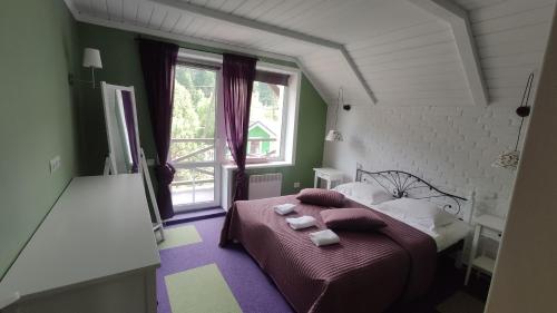a bedroom with a bed with pillows and a window at Villa Venterivka in Tatariv