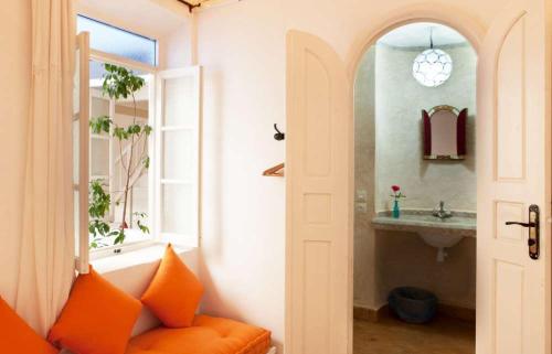 a bathroom with an orange couch next to a sink at La Casa Del Mar in Essaouira