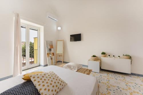 Habitación blanca con cama y TV en Il Poeta en Procida