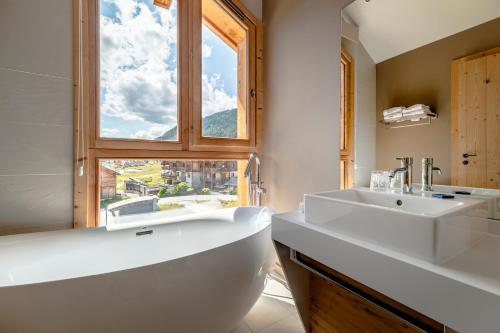 un bagno con ampia vasca, lavandino e finestra di Le Chalet Blanc Hôtel & Spa a Monginevro