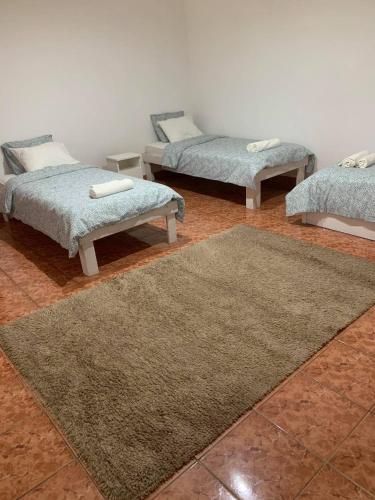 a room with three beds and a rug at Magic Vendégház in Abádszalók