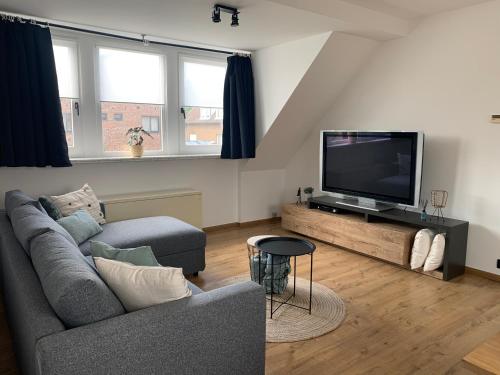 a living room with a couch and a flat screen tv at Vacanzamare in Wenduine