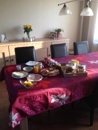uma mesa com uma toalha de mesa roxa com comida em Chez nous. em Couvin