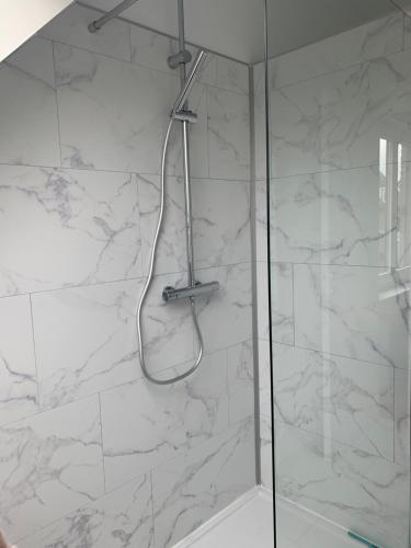 y baño con ducha y paredes de mármol blanco. en Vacanzamare, en Wenduine