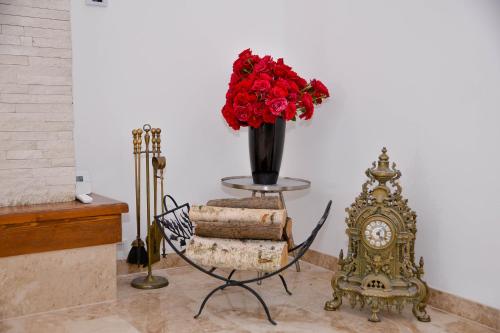 a vase of red roses sitting next to a clock at Boutique Damiani in Sibiu