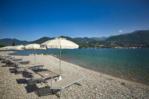 a row of lounge chairs and umbrellas on a beach at Park Hotel Casimiro in San Felice del Benaco