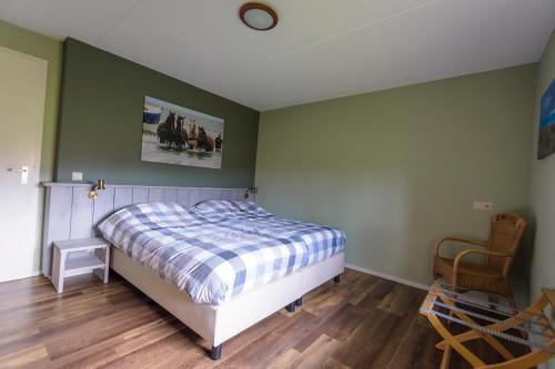 ein Schlafzimmer mit einem Bett und einem Stuhl in der Unterkunft Waddenresidentie Ameland in Buren