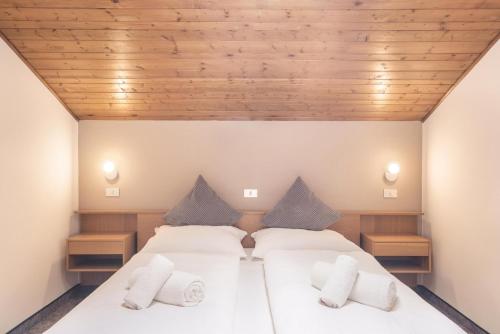 two beds in a room with wooden ceilings at Apt Hofer Heidi in Villabassa