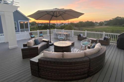 a deck with couches and a table and an umbrella at 2 Mi to Bethany Beach Upscale Coastal Home! in Ocean View