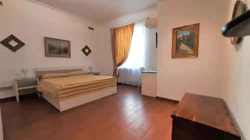 1 dormitorio con cama, ventana y suelo de madera en B&B Five, en Roma