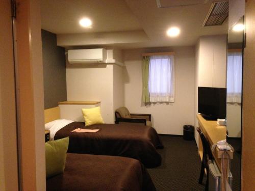 a hotel room with two beds and a television at Nagano Plaza Hotel in Nagano
