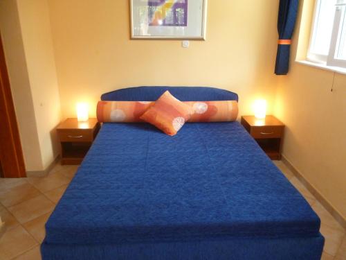 a blue bed in a room with two candles at Podgora Apartmani Sonja in Podgora