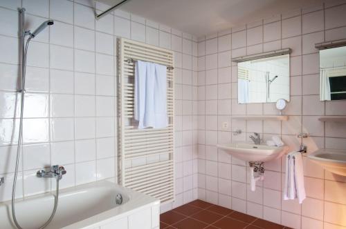 a bathroom with a tub and a sink at Hotel Restaurant Schlössli Sax in Sax