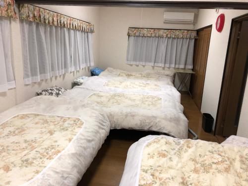 um quarto com três camas e cortinas em Youyousanso Modern A em Tsu