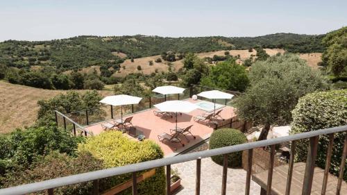 a balcony with tables and white umbrellas on a hill at Antico Casale Di Scansano Resort in Scansano