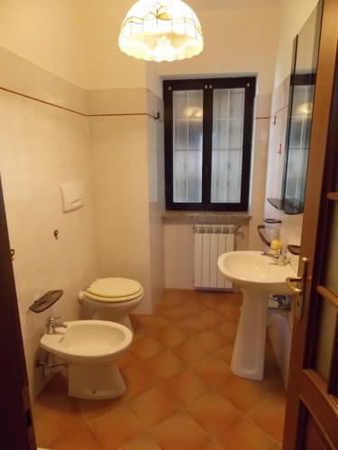 a bathroom with a toilet and two sinks and a window at Antica Dimora del Portico in Borgiallo