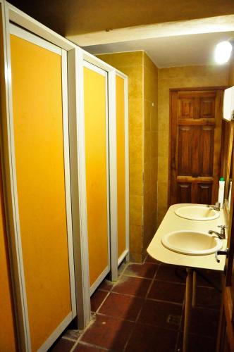 a bathroom with two sinks and a toilet with yellow walls at Giramundo Hostel Purmamarca in Purmamarca