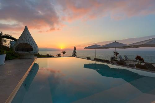 a swimming pool with a sunset in the background at Maxwell Residences at Indah in Puerto Vallarta