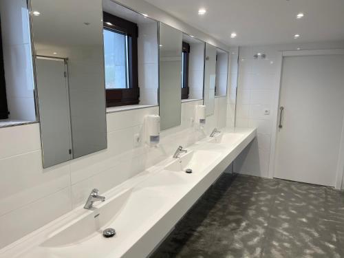 a white bathroom with three sinks and mirrors at Casa Galego in Fonfría