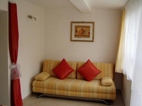 a living room with a couch with two red pillows at Podgora Apartmani Sonja in Podgora