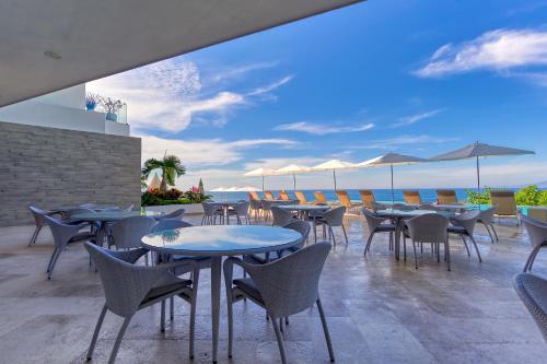a patio with tables and chairs and the ocean at Maxwell Residences at Indah in Puerto Vallarta