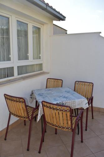 a table and chairs on a patio with a window at Podgora Apartmani Sonja in Podgora